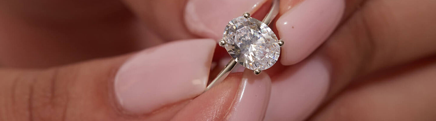 Hand holding an oval yellow gold engagement ring